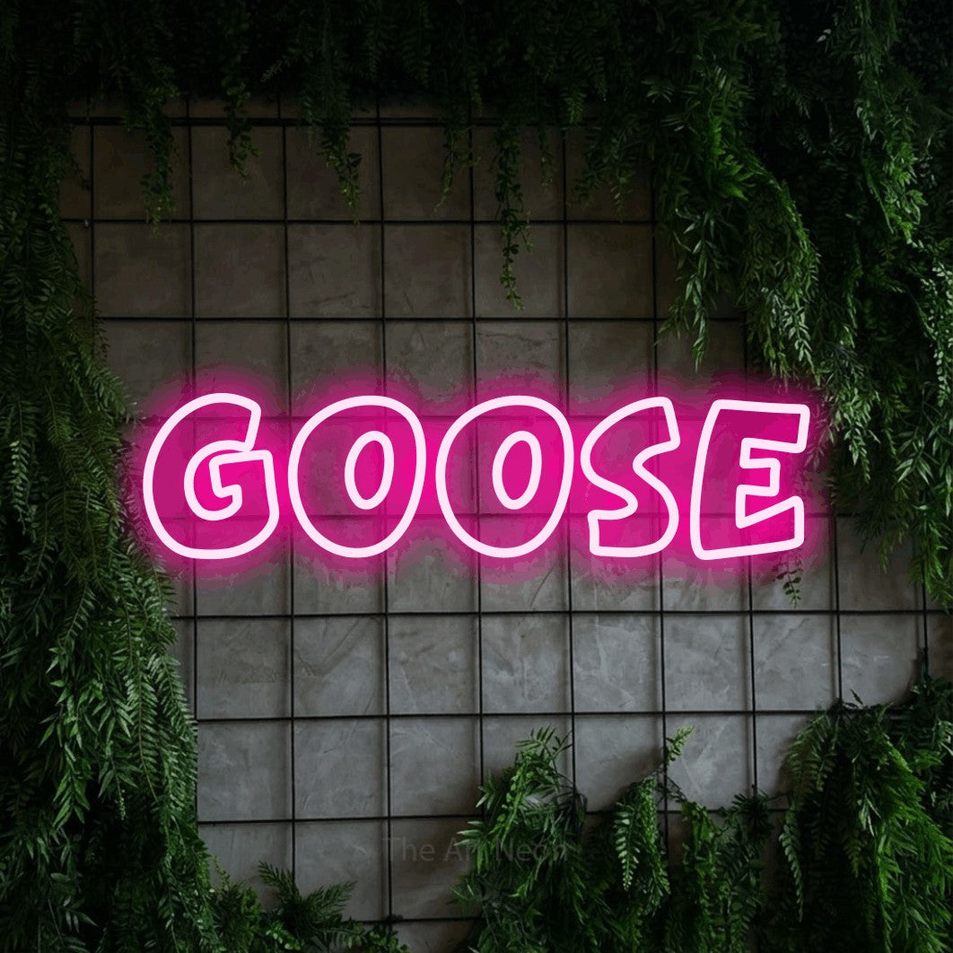 Hot pink outline-style LED neon sign reading "Goose" against a green grid wall with foliage