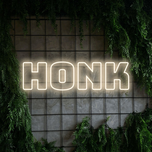 Enseigne néon à DEL à lumière blanche chaude, de style contour, affichant « Honk » sur un mur quadrillé vert avec du feuillage