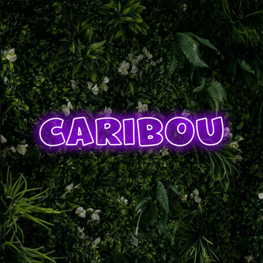 Enseigne néon à DEL à lumière violette, de style contour, affichant « Caribou » sur un mur de feuillage vert