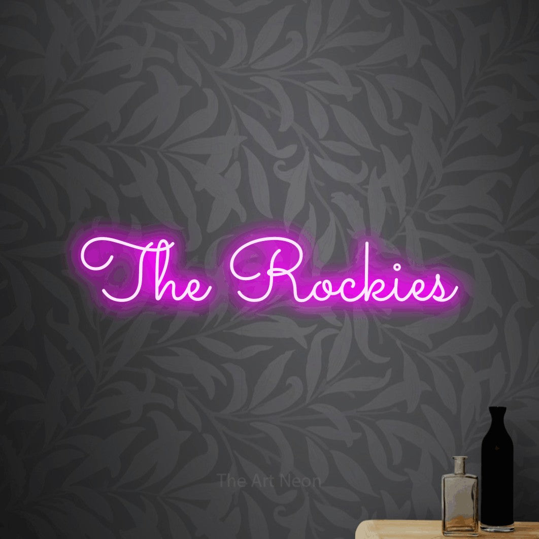 Pink LED neon sign reading "The Rockies" against light grey floral wallpaper
