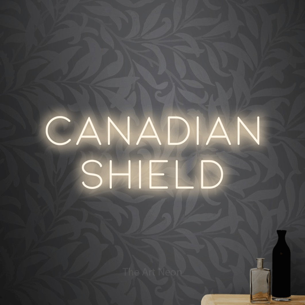 Warm white LED neon sign reading "Canadian Shield" against light grey floral wallpaper