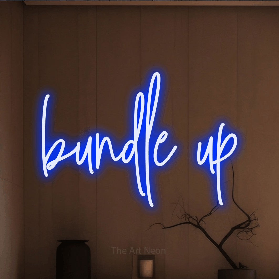 Blue script-style LED neon sign reading "Bundle Up" against a warm brown wall
