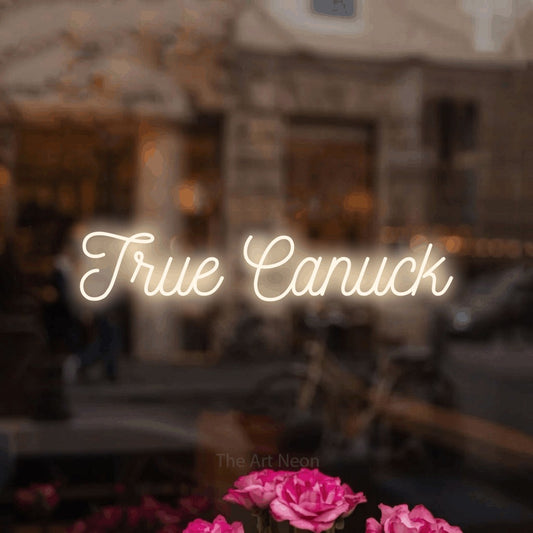 Enseigne néon à DEL à lumière blanche chaude, de style manuscrit, affichant « True Canuck » dans un intérieur de café légèrement flou