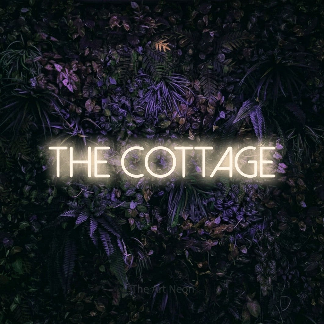 Warm white LED neon sign reading "The Cottage" against a purple floral wall