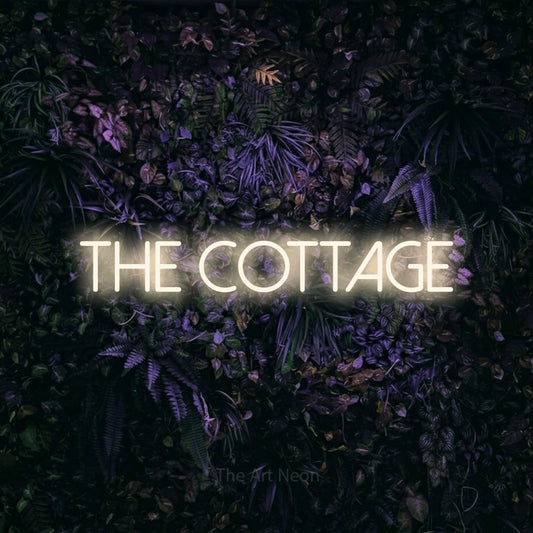 Warm white LED neon sign reading "The Cottage" against a purple floral wall