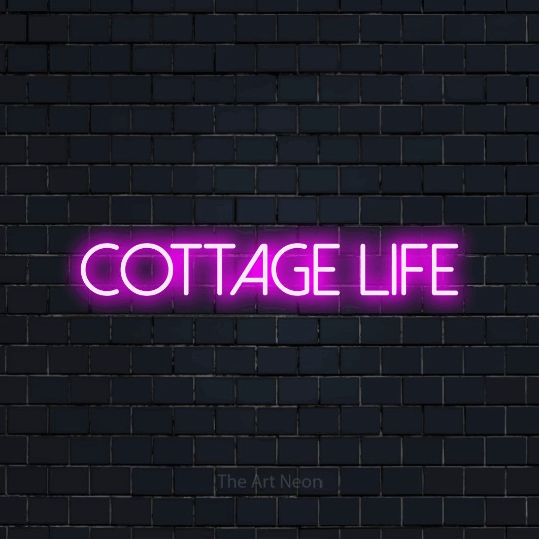 Pink LED neon sign reading "Cottage Life" against a dark navy brick wall