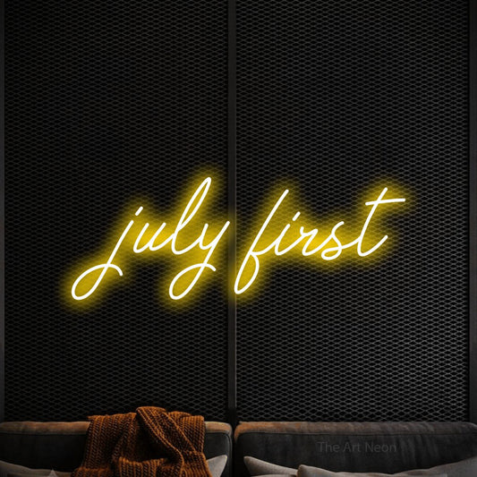 Yellow script-style LED neon sign reading "July First" against a black textured wall