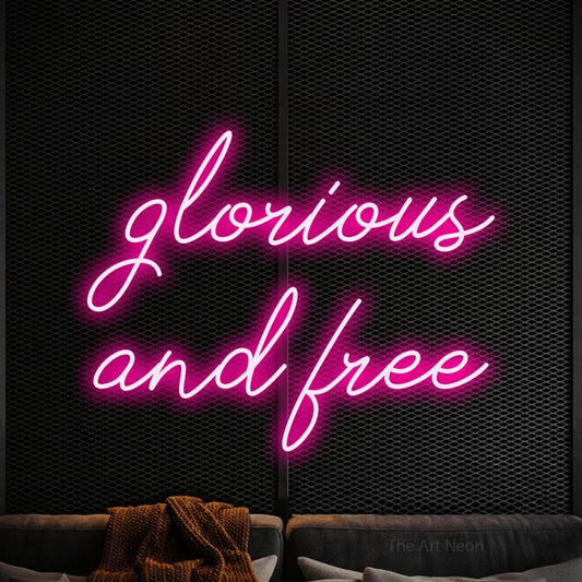 Hot pink script-style LED neon sign reading "Glorious and Free" against a black textured wall
