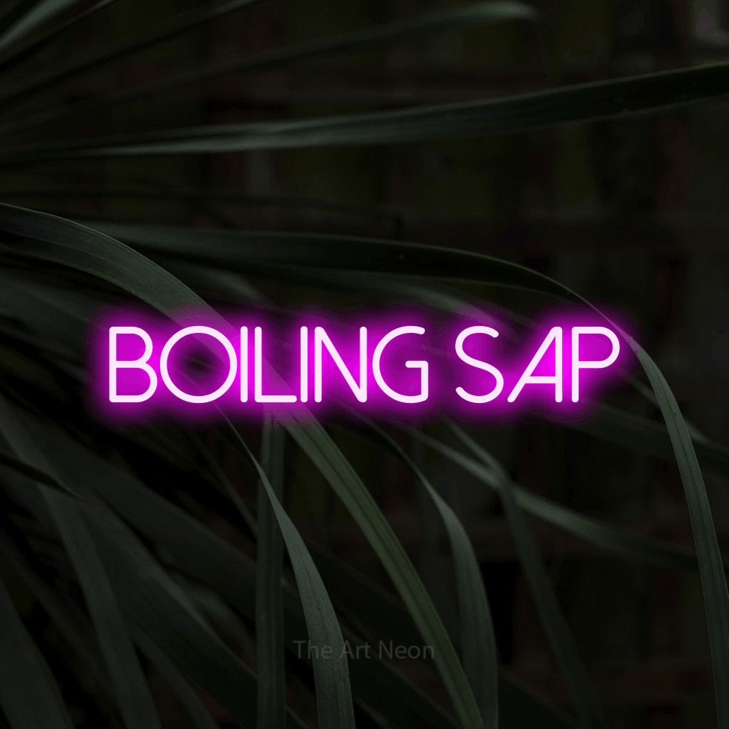Pink LED neon sign reading "Boiling Sap" against dark tropical leaves