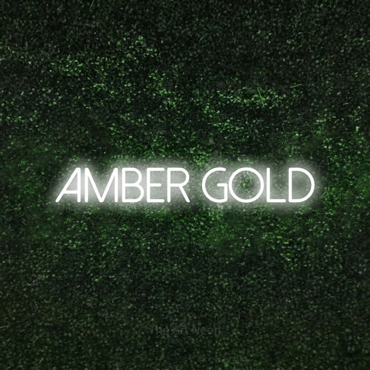 Cool white LED neon sign reading "Amber Gold" against a textured green moss wall