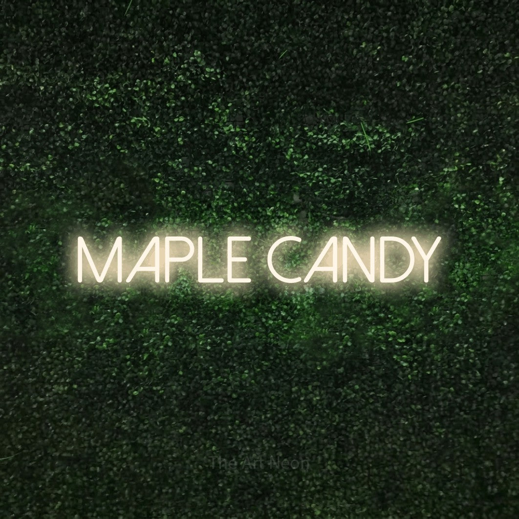 Warm white LED neon sign reading "Maple Candy" against a textured green moss wall