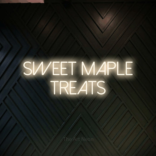 Warm white LED neon sign reading "Sweet Maple Treats" against a dark geometric wood wall