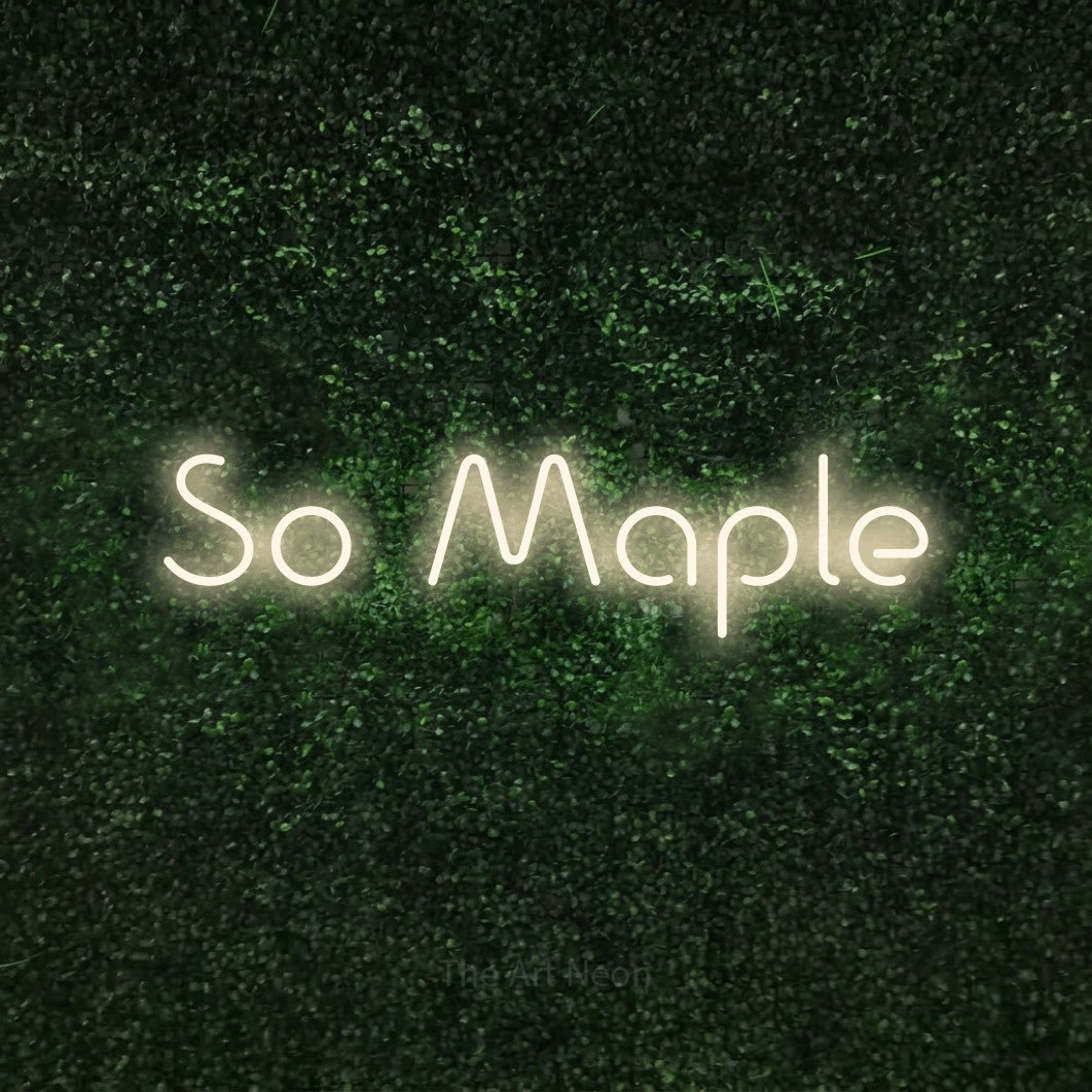 Warm white LED neon sign reading "So Maple" against a textured green moss wall