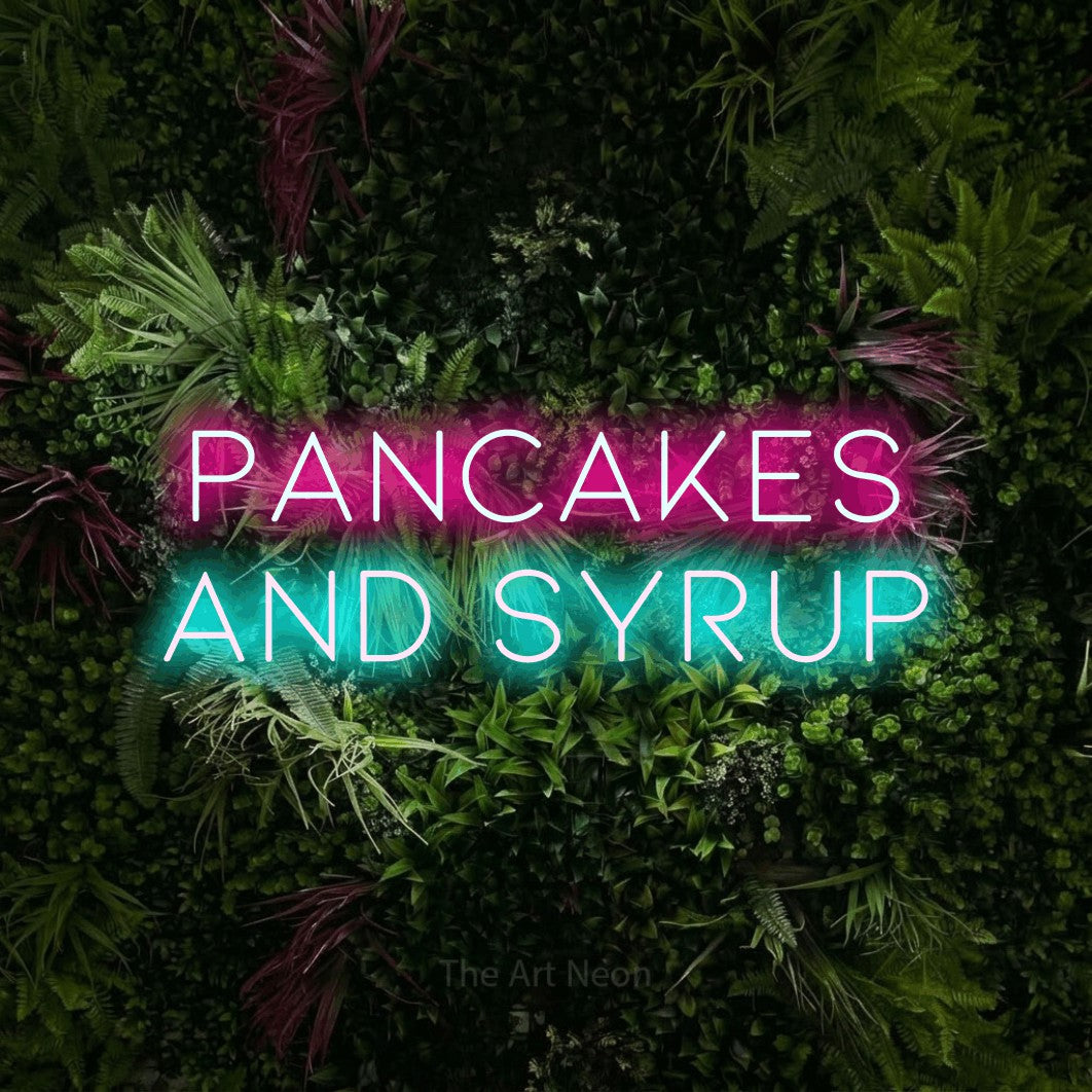 Ice blue and hot pink LED neon sign reading "Pancakes and Syrup" against a lush garden wall with pink flowers