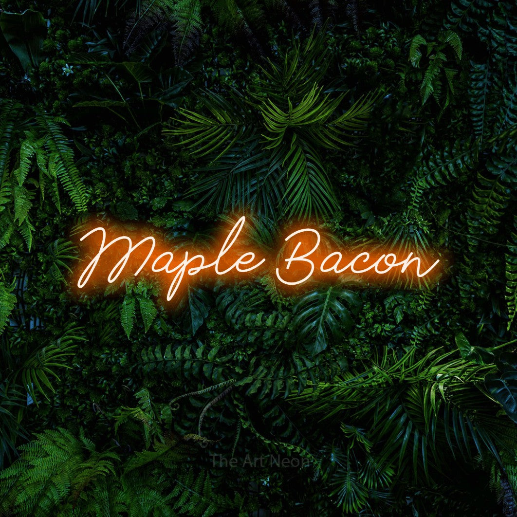 Orange script-style LED neon sign reading "Maple Bacon" against a dense tropical foliage wall