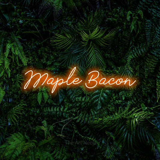 Orange script-style LED neon sign reading "Maple Bacon" against a dense tropical foliage wall