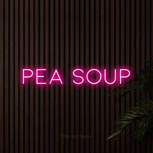 Hot pink LED neon sign reading "Pea Soup" against dark wooden slats