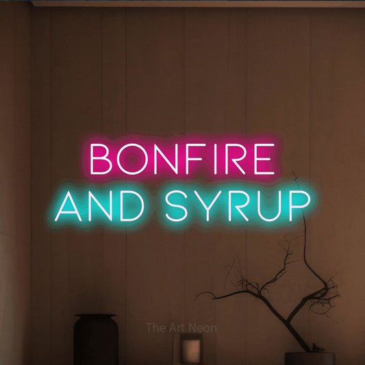 Ice blue and hot pink LED neon sign reading "Bonfire and Syrup" against a warm brown wall