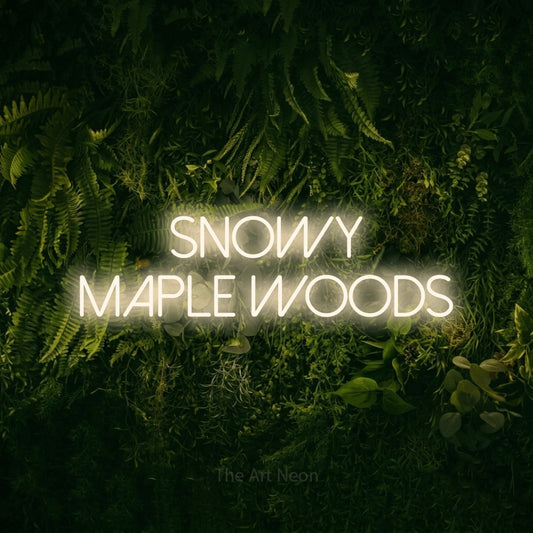 Warm white LED neon sign reading "Snowy Maple Woods" against a moss-covered green wall