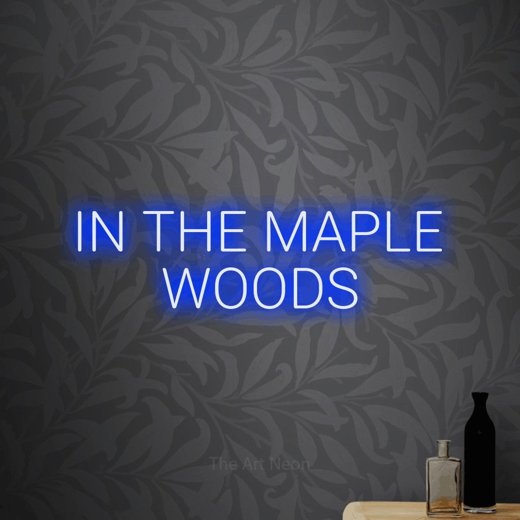 Blue LED neon sign reading "In the Maple Woods" against light grey floral wallpaper