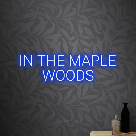 Blue LED neon sign reading "In the Maple Woods" against light grey floral wallpaper