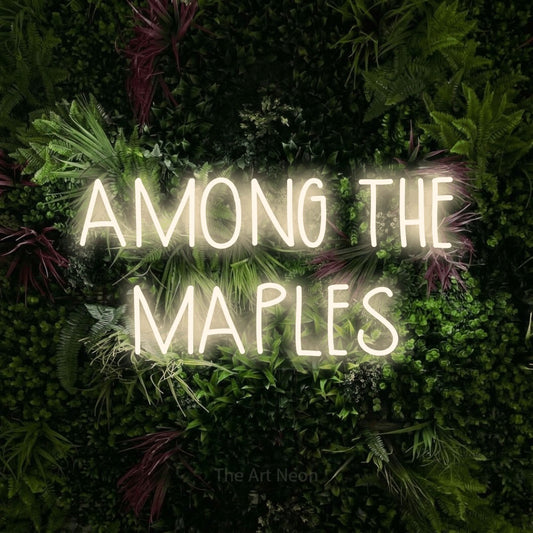 Warm white LED neon sign reading "Among the Maples" against a lush garden wall with pink flowers