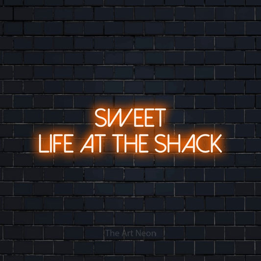 Orange LED neon sign reading "Sweet Life at the Shack" against a dark navy brick wall