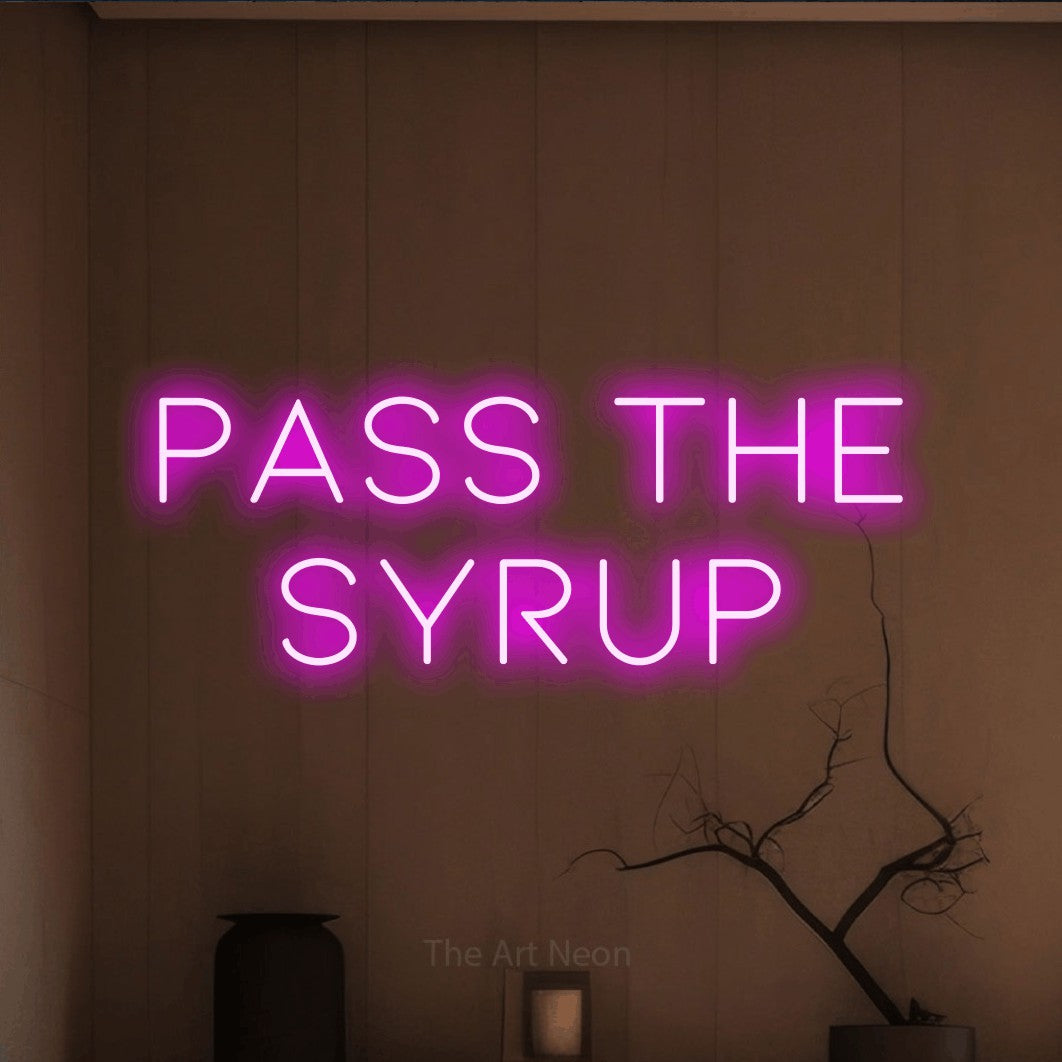 Pink LED neon sign reading "Pass the Syrup" against a warm brown wall