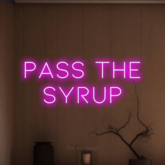 Pink LED neon sign reading "Pass the Syrup" against a warm brown wall