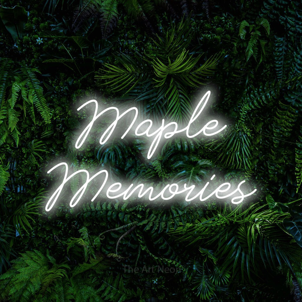 Cool white script-style LED neon sign reading "Maple Memories" against a dense tropical foliage wall