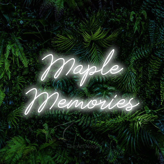 Cool white script-style LED neon sign reading "Maple Memories" against a dense tropical foliage wall