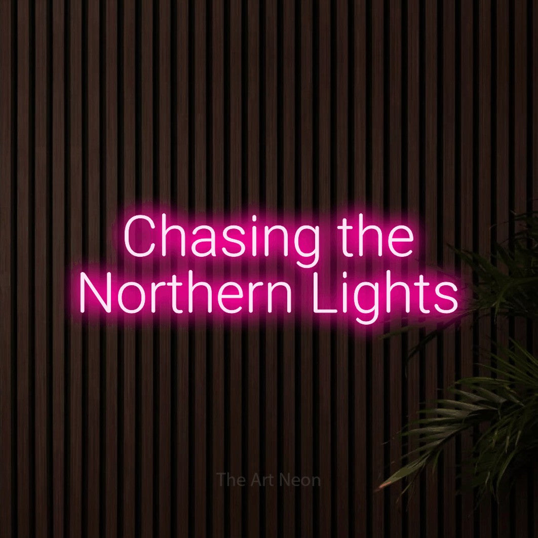 Hot pink LED neon sign reading "Chasing the Northern Lights" against dark wooden slats