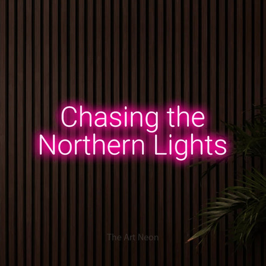 Hot pink LED neon sign reading "Chasing the Northern Lights" against dark wooden slats