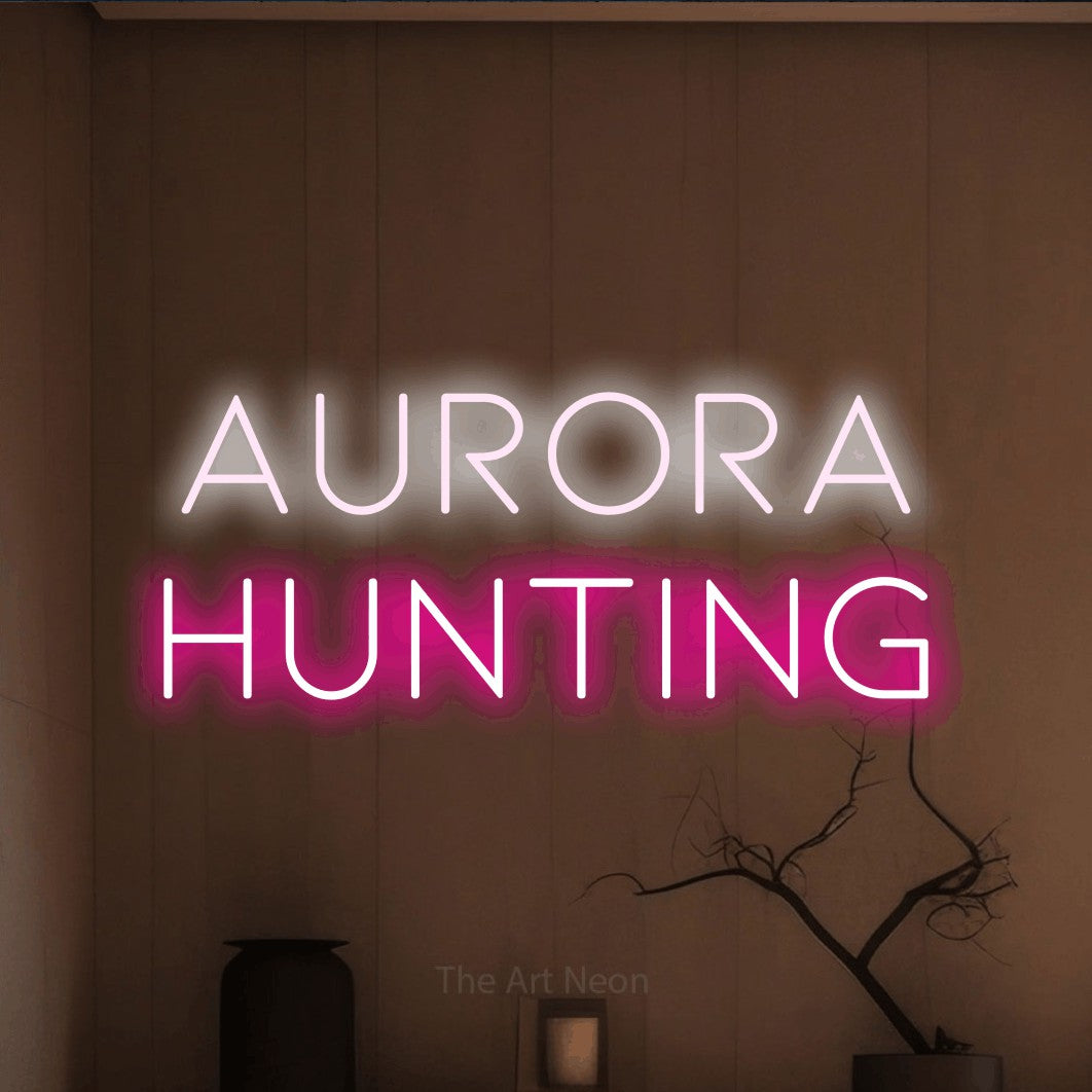 Hot pink and cool white LED neon sign reading "Aurora Hunting" against a warm brown wall