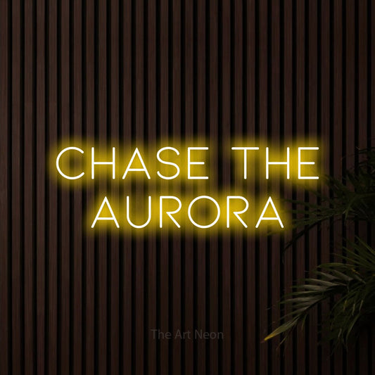 Yellow LED neon sign reading "Chase the Aurora" against dark wooden slats