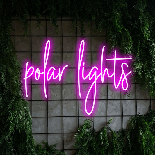 Pink script-style LED neon sign reading "Polar Lights" against a green grid wall with foliage