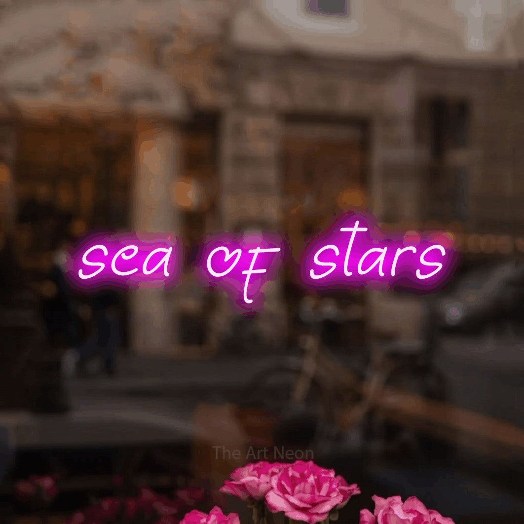 Pink LED neon sign reading "Sea of Stars" in a softly blurred café interior