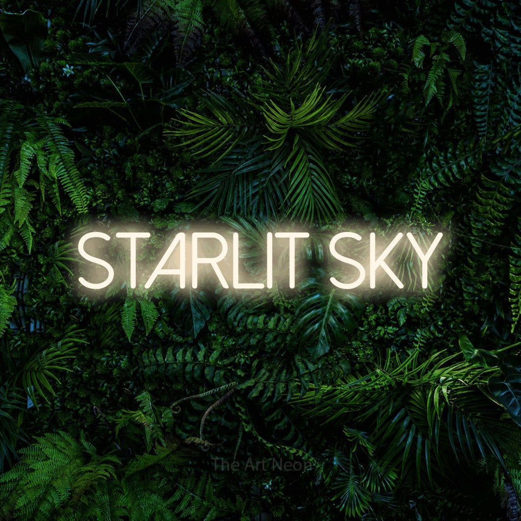 Warm white LED neon sign reading "Starlit Sky" against a dense tropical foliage wall