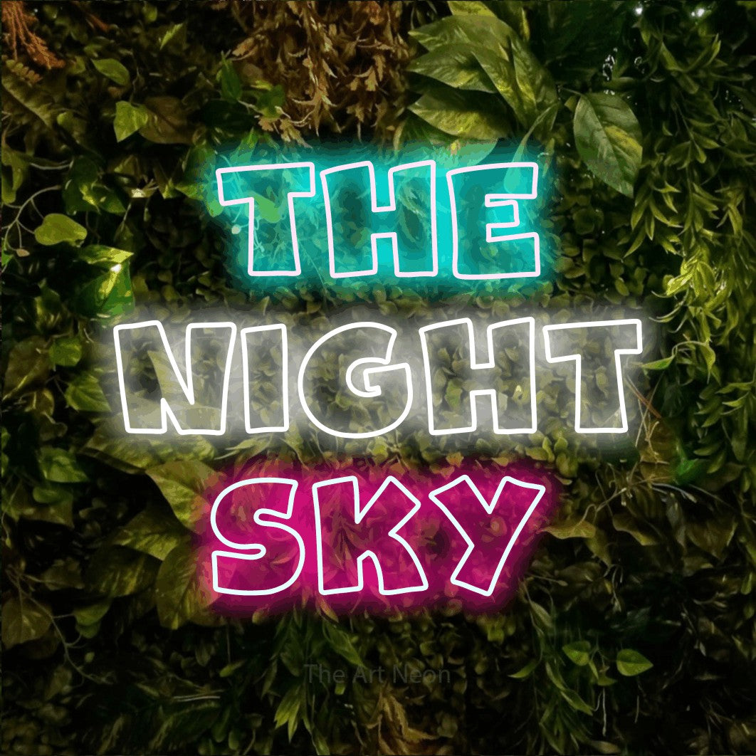 Multicolour outline-style LED neon sign reading "The Night Sky" against a textured moss and foliage wall