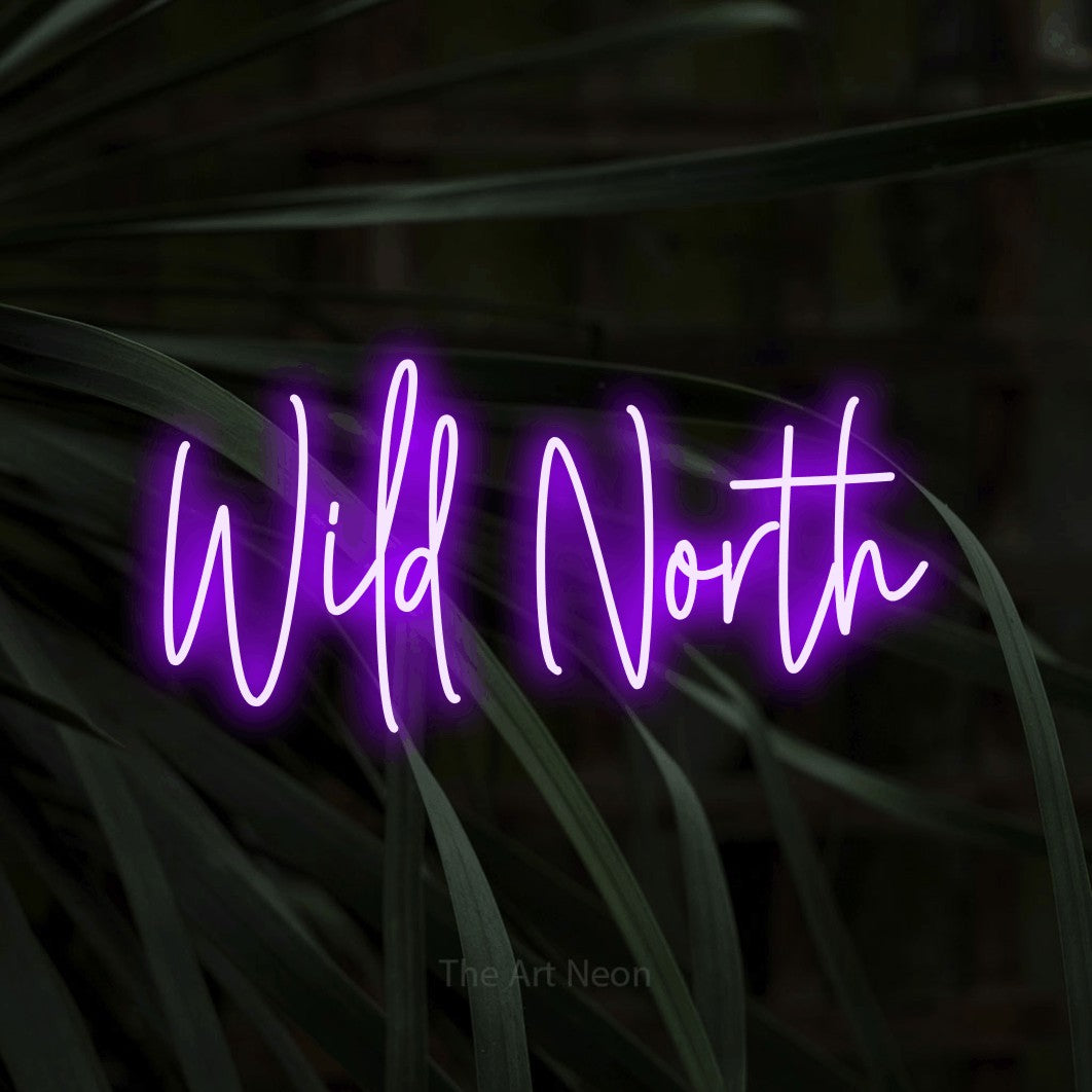 Purple script-style LED neon sign reading "Wild North" against dark tropical leaves