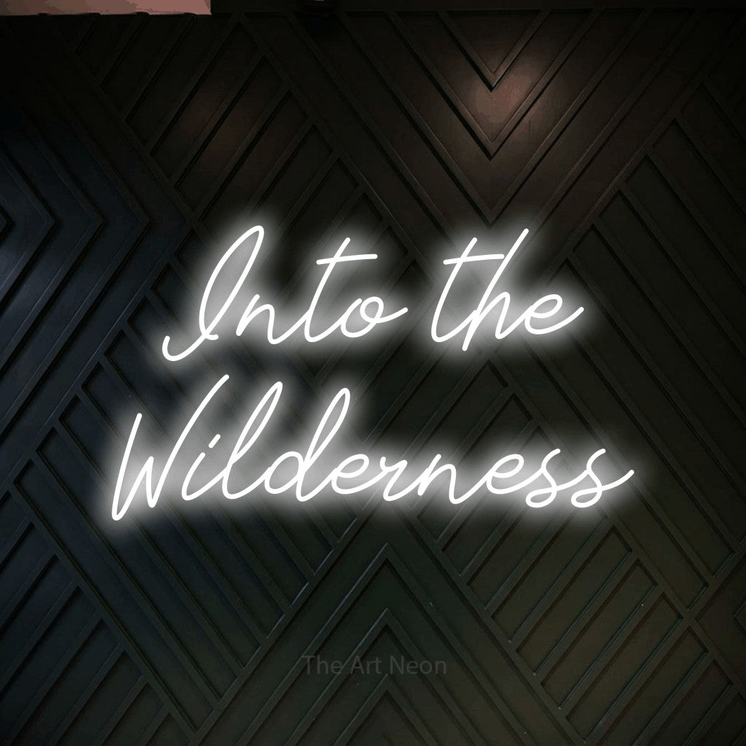 Cool white script-style LED neon sign reading "Into the Wilderness" against a dark geometric wood wall