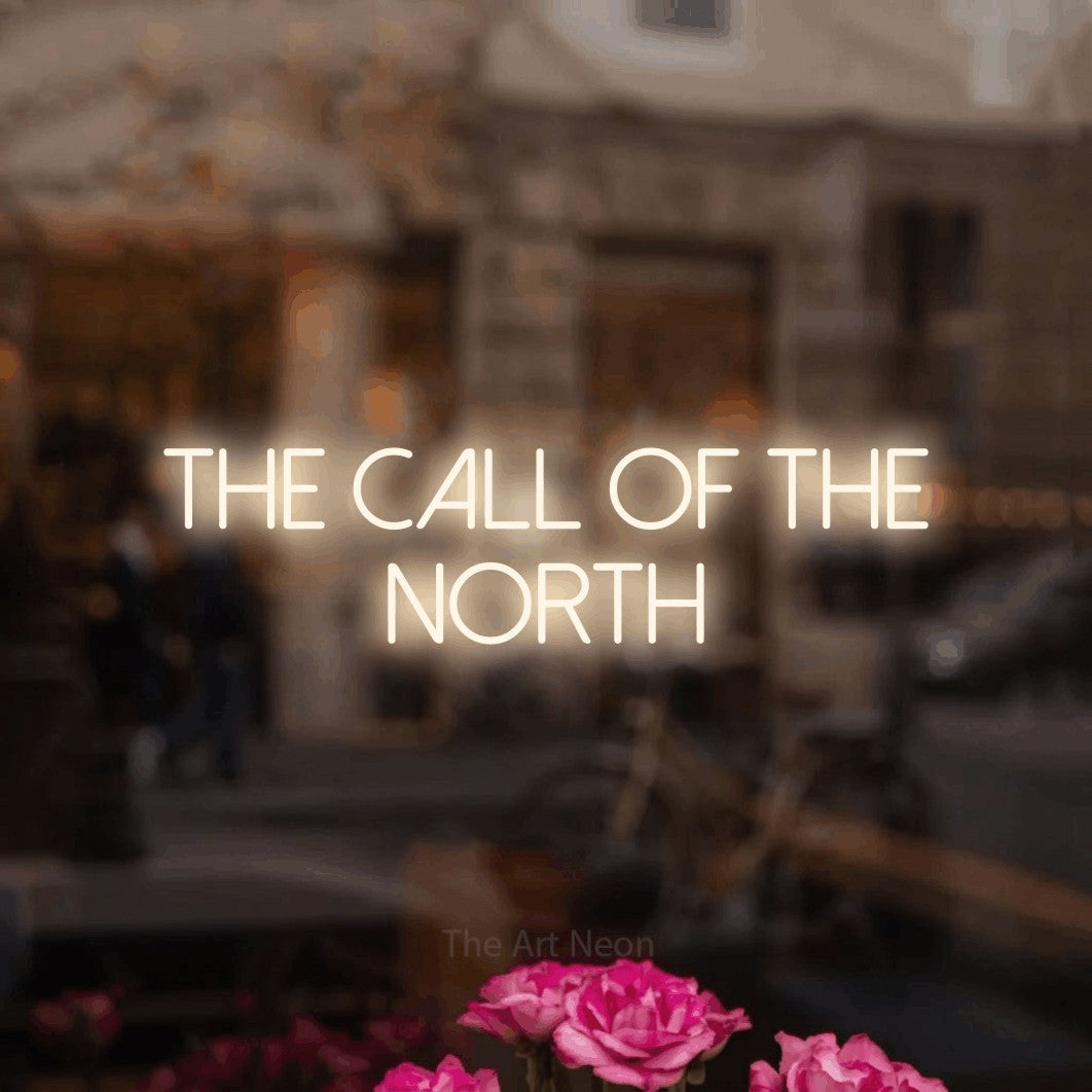 Warm white LED neon sign reading "The Call of the North" in a softly blurred café interior