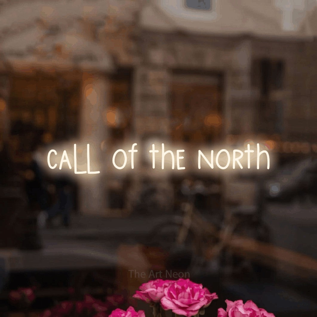 Warm white LED neon sign reading "Call of the North" in a softly blurred café interior