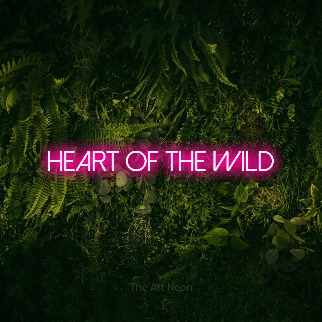 Enseigne néon à DEL à lumière rose vif, affichant « Heart of the Wild » sur un mur vert couvert de mousse