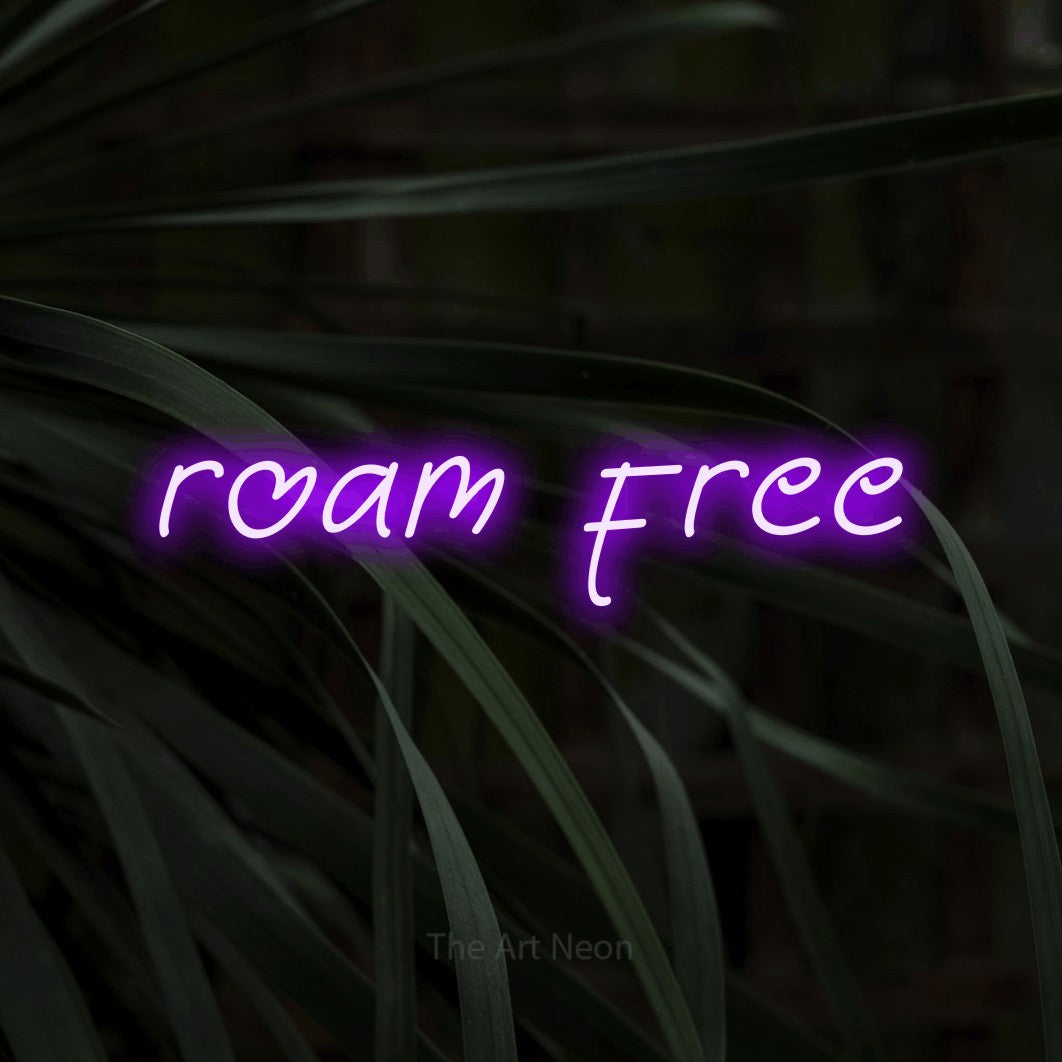 Purple LED neon sign reading "Roam Free" against dark tropical leaves