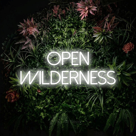 Cool white LED neon sign reading "Open Wilderness" against a flowering garden wall