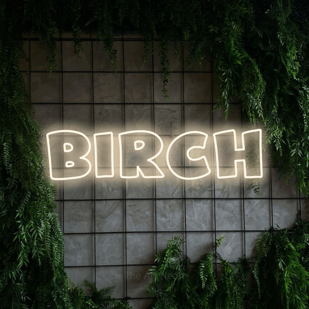 Warm white outline-style LED neon sign reading "Birch" against a green grid wall with foliage