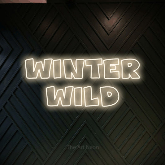 Warm white outline-style LED neon sign reading "Winter Wild" against a dark geometric wood wall