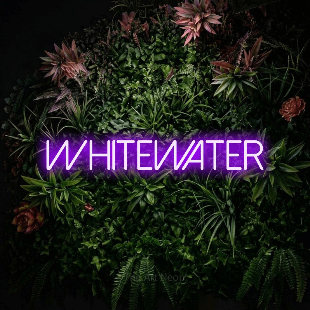 Purple LED neon sign reading "Whitewater" against a flowering garden wall