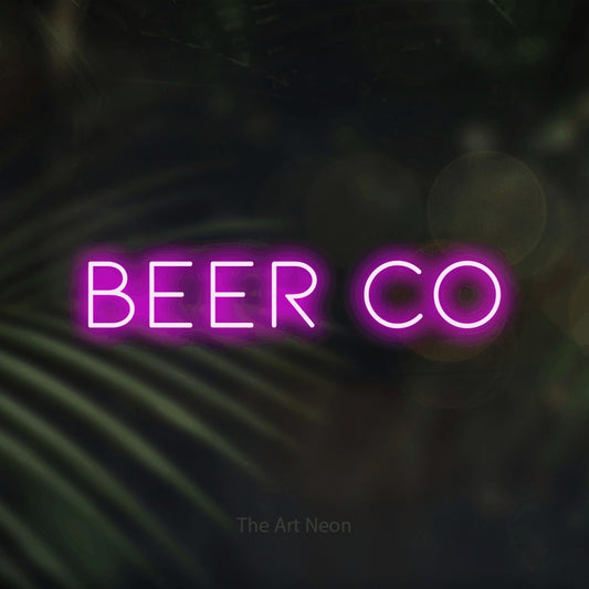 Pink LED neon sign reading "Beer Co" against dark blurred palm leaves